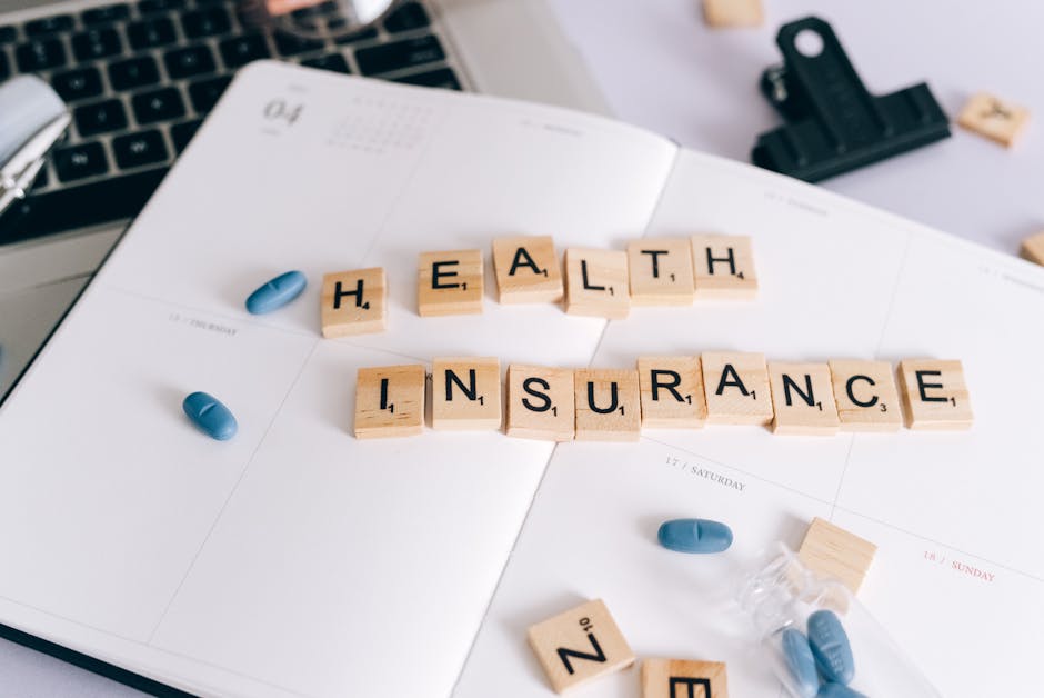 term life insurance - Scrabble tiles spelling 'Health Insurance' on planner with pills and laptop, symbolizing healthcare planning.