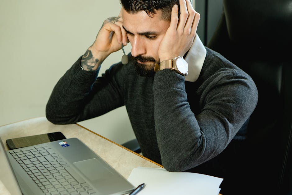 help desk software - Bearded man in a call center focused on providing customer support using a laptop.